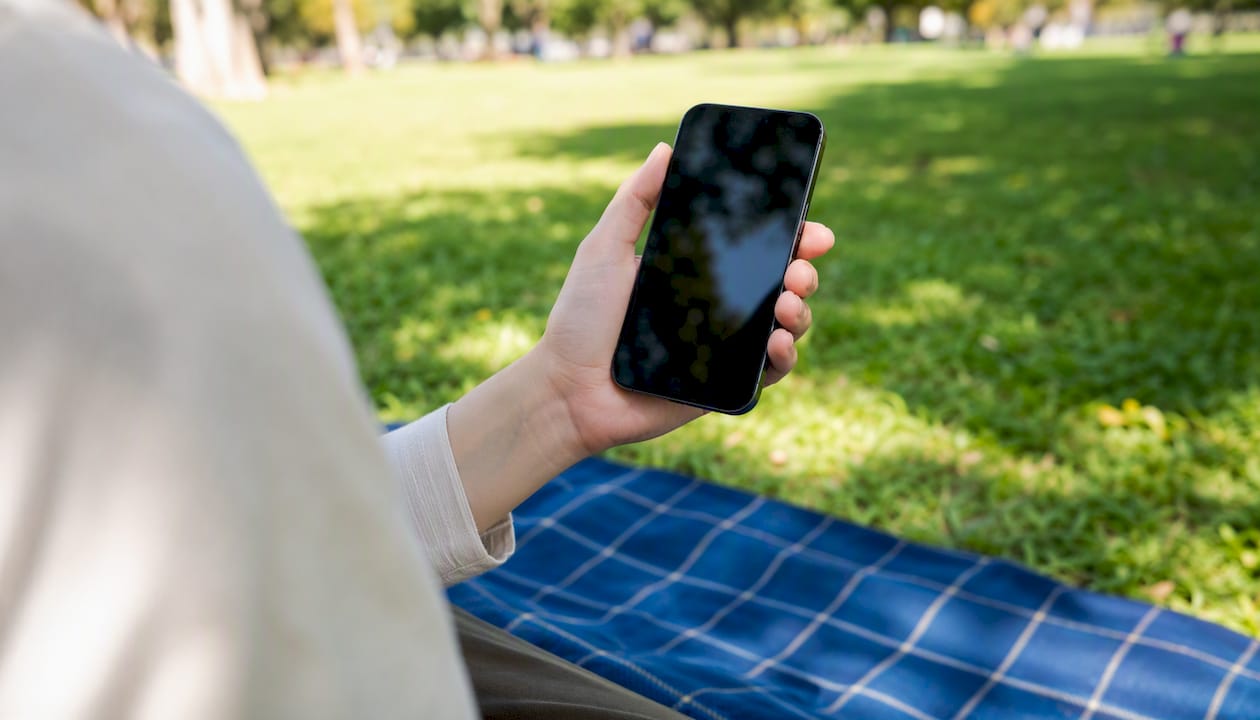 Hand holding smartphone in café environment