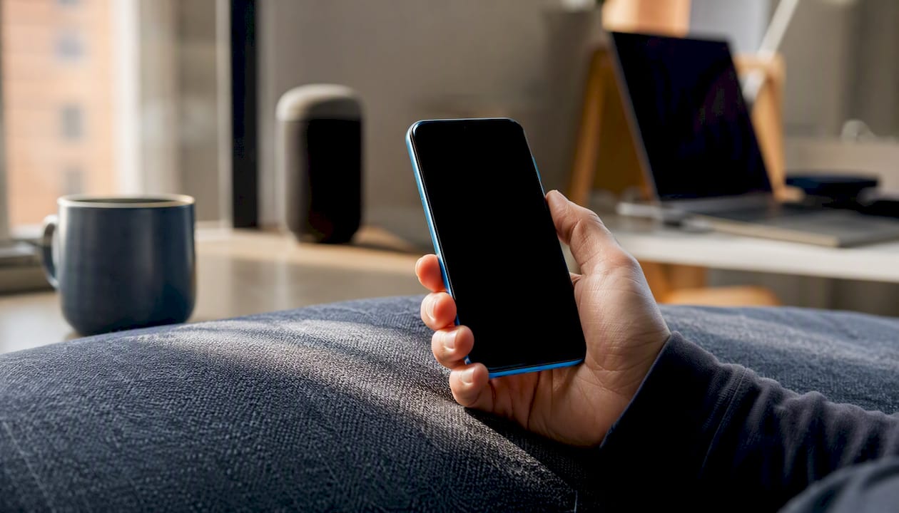 Hand holding smartphone with dark screen